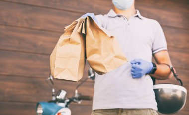 Teslimatçı, yemeği müşteriye motosikletiyle teslim eder.