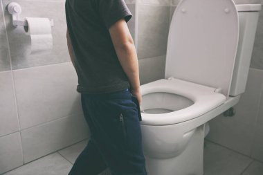 Çocuk tuvaletteki klozete işiyor.
