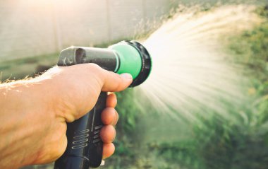 Adam bahçedeki bitkileri suluyor.