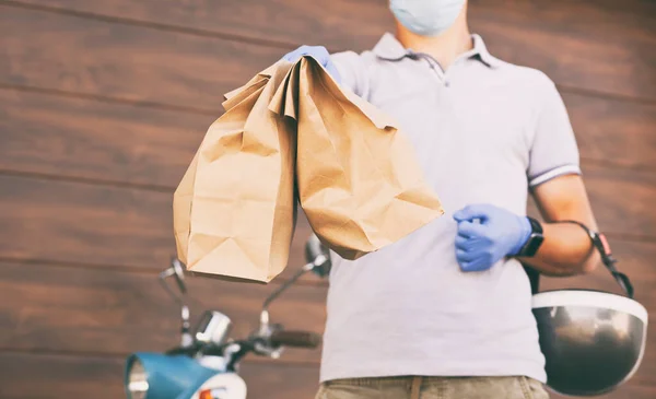 The delivery guy delivers the food to the customer by his moped