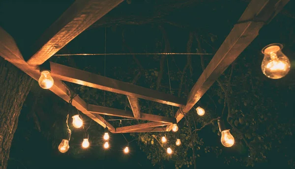 The garland from the retro bulbs hanging on the wooden planks