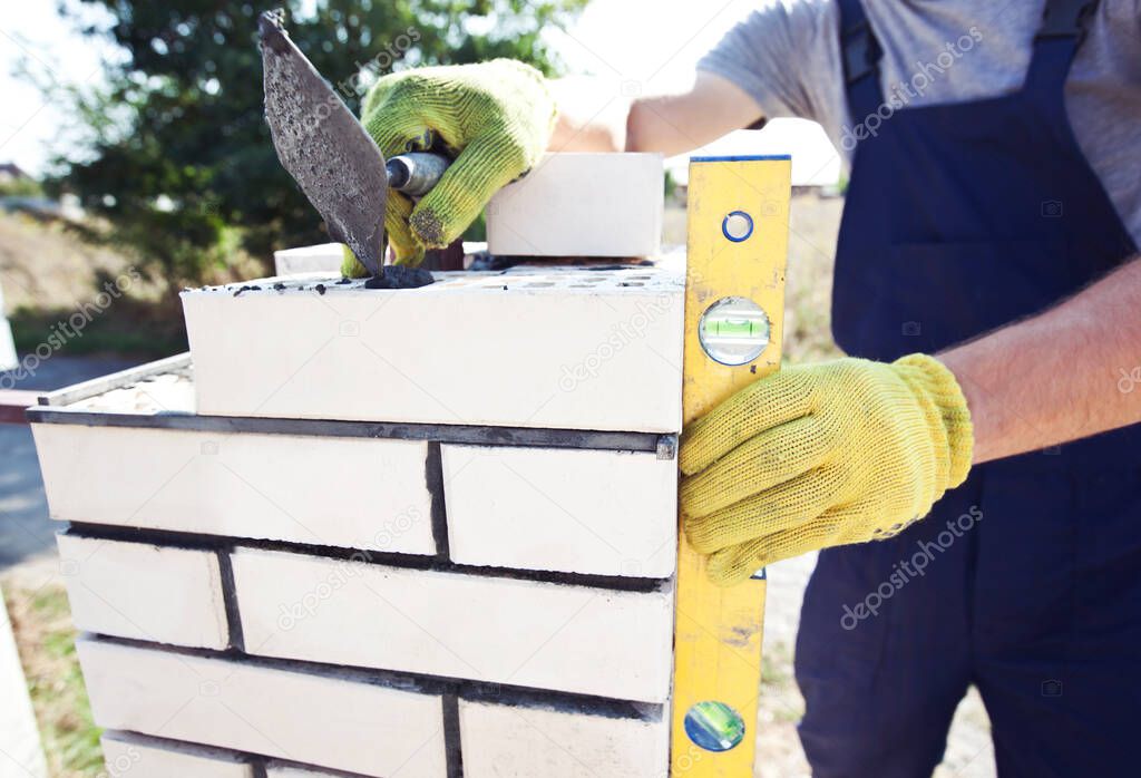 A worker builds a fence post from bricks