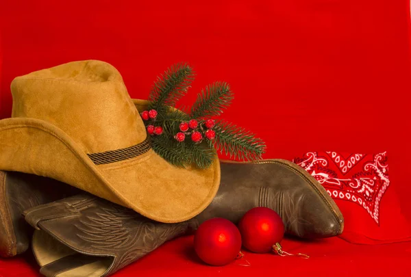 Cowboy Christmas card.American West traditional boots and hat on christmas red background for text