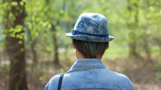Ung kvinna i hatt promenader i skogen träd — Stockvideo