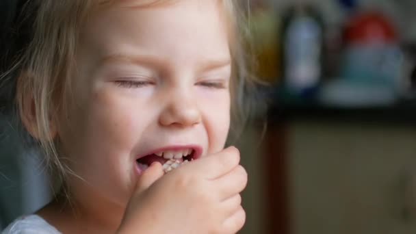 Снимок ребенка, облизывающего еду с пальца. Затем она поворачивается и улыбается . — стоковое видео