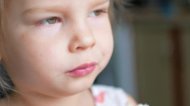 Plan d'un enfant léchant de la nourriture de son doigt. Puis elle se retourne et sourit . — Video