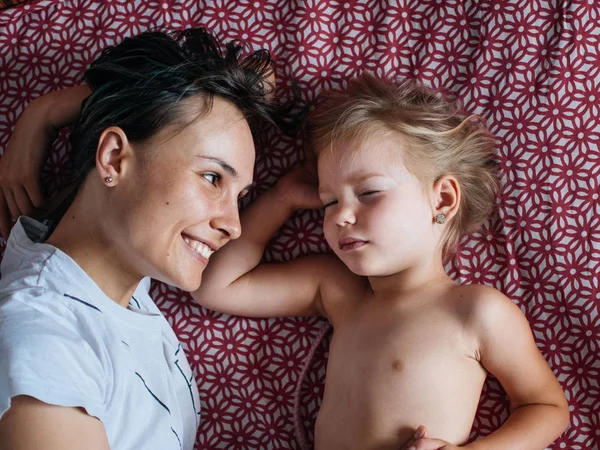 Mom and daughter in bed, the morning the baby wakes up and hugs mother. The concept of a happy family life