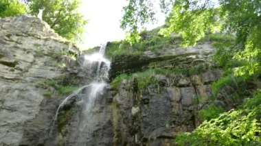 bir kayalık ve yosunlu uçurumun kenarında dökülen gibi uzun ince bir şelale destek vurdu