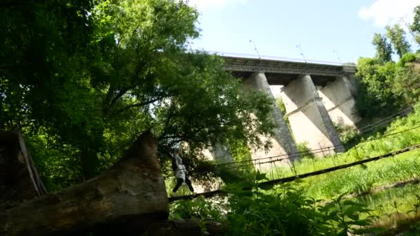 Flicka traveler står på en bro över en flod i berg — Stockvideo