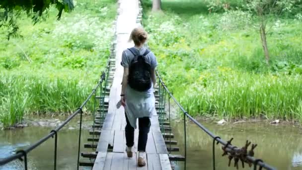 Girl traveler standing on a bridge across a mountain river — Stock Video