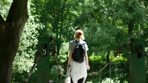 Girl traveler standing on a bridge across a mountain river — Stock Video