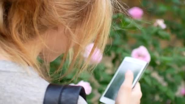 De blonde thumbs de nieuws-tape in de telefoon. Achteraanzicht. — Stockvideo