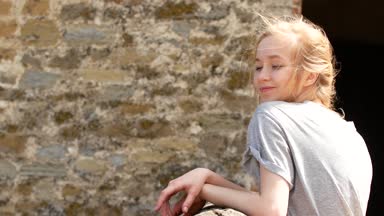 Kızıl saçlı kız rüzgar eski kalenin arka plan üzerinde duruyor.