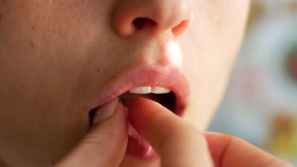 Uma mulher coloca um comprimido em sua boca e bebe com água, close-up — Vídeo de Stock