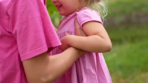 Vacker ung mor omfamnar hennes söta dotter med gul ljusa blommor på sommaren bakgrund. — Stockvideo
