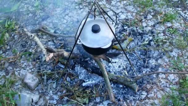 Boiling pot of water on fires outdoors — Stock Video