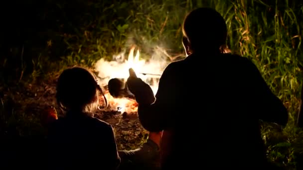 Mãe e filha sentam-se à noite em volta de uma fogueira brilhante — Vídeo de Stock