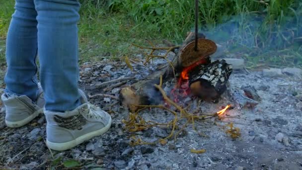 Una niña está preparando pan en la hoguera. Niño cerca del fuego en la campaña — Vídeo de stock