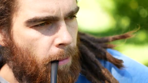 Portrait d'homme hipster avec dreadlocks fumant de la cigarette. Vue latérale — Video