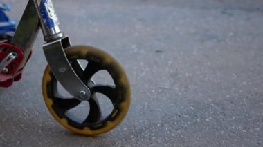 Çocuk ile bir scooter bir yaz parkta gidiyor. Çocukluk, yaz, mutluluk ve spor etkinlik kavramı