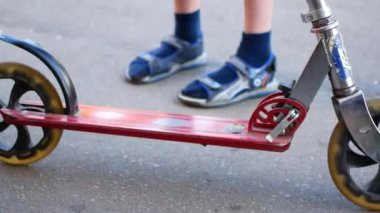 Çocuk ile bir scooter bir yaz parkta gidiyor. Çocukluk, yaz, mutluluk ve spor etkinlik kavramı