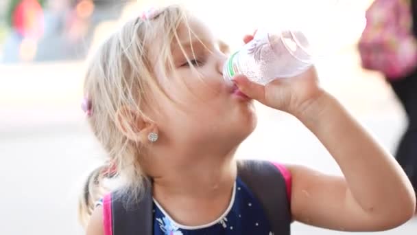 Das kinderblonde Mädchen trinkt gerne Wasser im Freien. ein Kind trinkt sauberes Wasser aus einer Flasche — Stockvideo