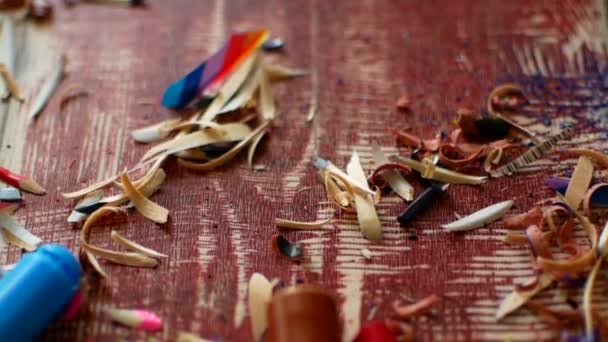 Colored pencils with pencil shavings on wooden background — Stock Video