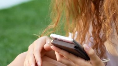 Onun cep telefonu kısa mesaj okuma bir yaz parkta rahat genç bayan portresi.