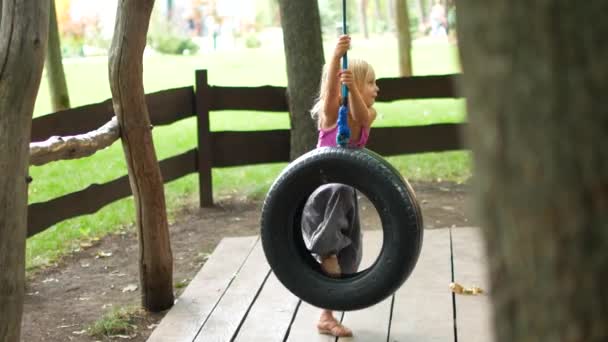 Tiro de menina sorrindo no balanço do pneu — Vídeo de Stock
