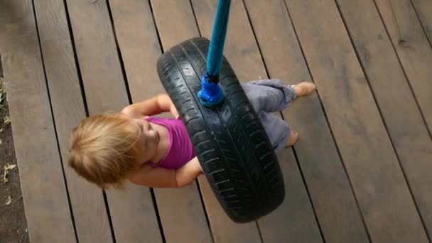 Aufnahme eines lächelnden Mädchens auf einer Reifenschaukel — Stockvideo