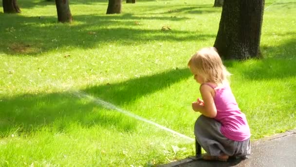 Petite fille dans le parc sous les gouttes de tampon d'arrosage — Video