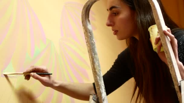 Κορίτσι καλλιτέχνης ζωγραφίζει ένα τοίχο στέκεται σε μια σκάλα — Αρχείο Βίντεο
