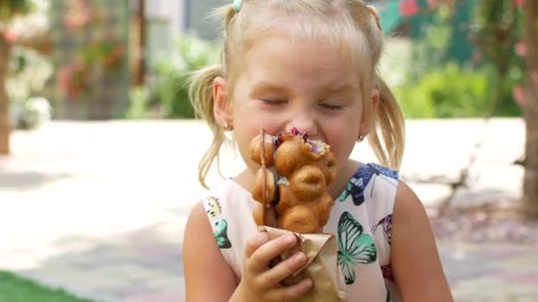 Uma menina maravilhosa pequena está comendo waffles com frutas e sorvete. O café de verão — Vídeo de Stock