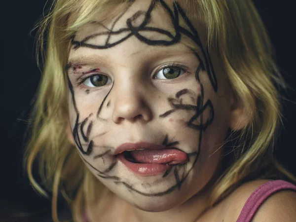 Het kleine meisje haar gezicht geschilderd met een marker. Make-up voor Halloween. — Stockfoto