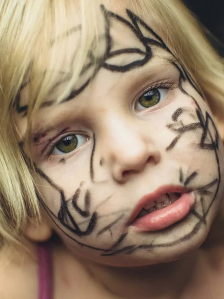 Het kleine meisje haar gezicht geschilderd met een marker. Make-up voor Halloween. — Stockfoto