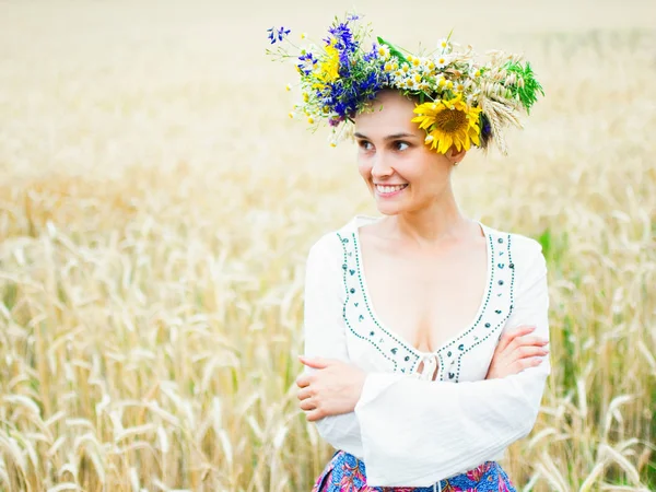 Ragazza ucraina in una bella ghirlanda passeggiate attraverso il prato estivo. La ragazza è vestita con abiti etnici con ricami. Festa di Ivan Kupala — Foto Stock