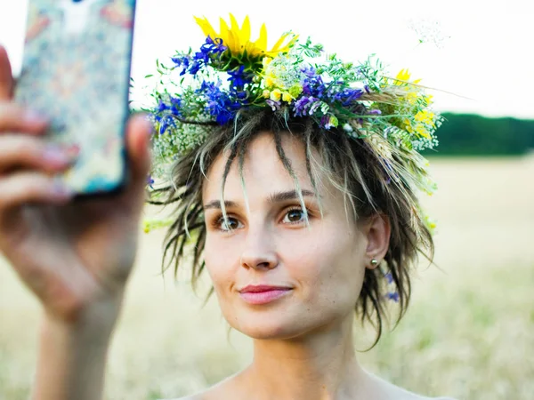 Attraktive lustige Hippie-Frau auf dem Feld bei Sonnenuntergang macht ein Selfie — Stockfoto