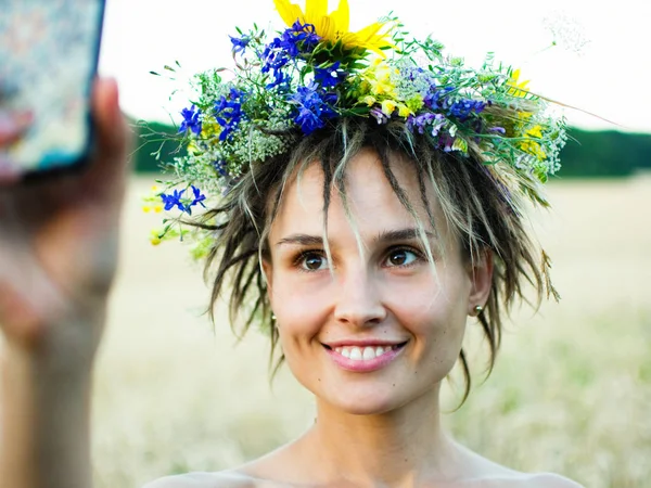 Attraktive lustige Hippie-Frau auf dem Feld bei Sonnenuntergang macht ein Selfie — Stockfoto