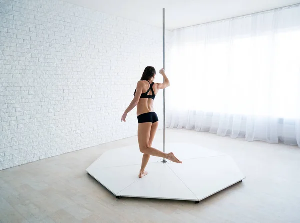 Giovane sottile sexy pole dance donna in lingerie nera su sfondo bianco parete — Foto Stock