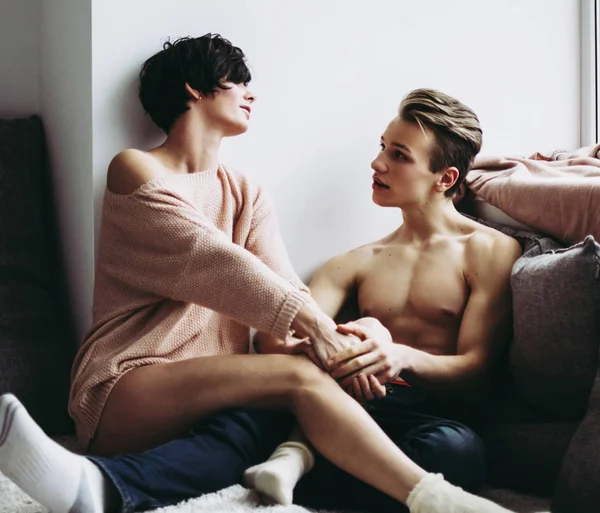 Mooie gelukkige paar zittend op de vloer op een kleine mat in een ruime lichte kamer. — Stockfoto