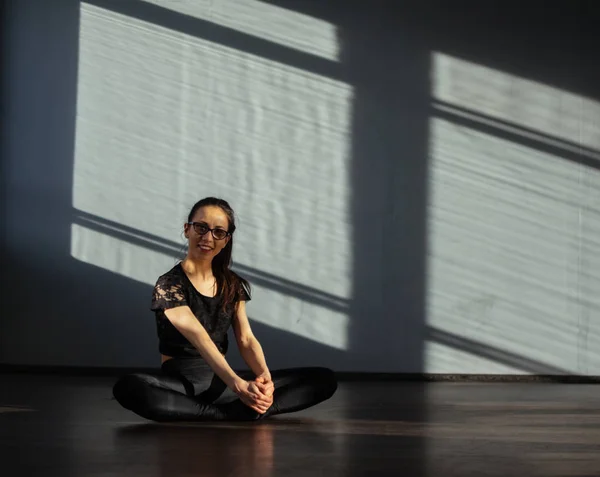 Una chica en el salón de baile se sienta en el suelo y se calienta antes de entrenar . —  Fotos de Stock