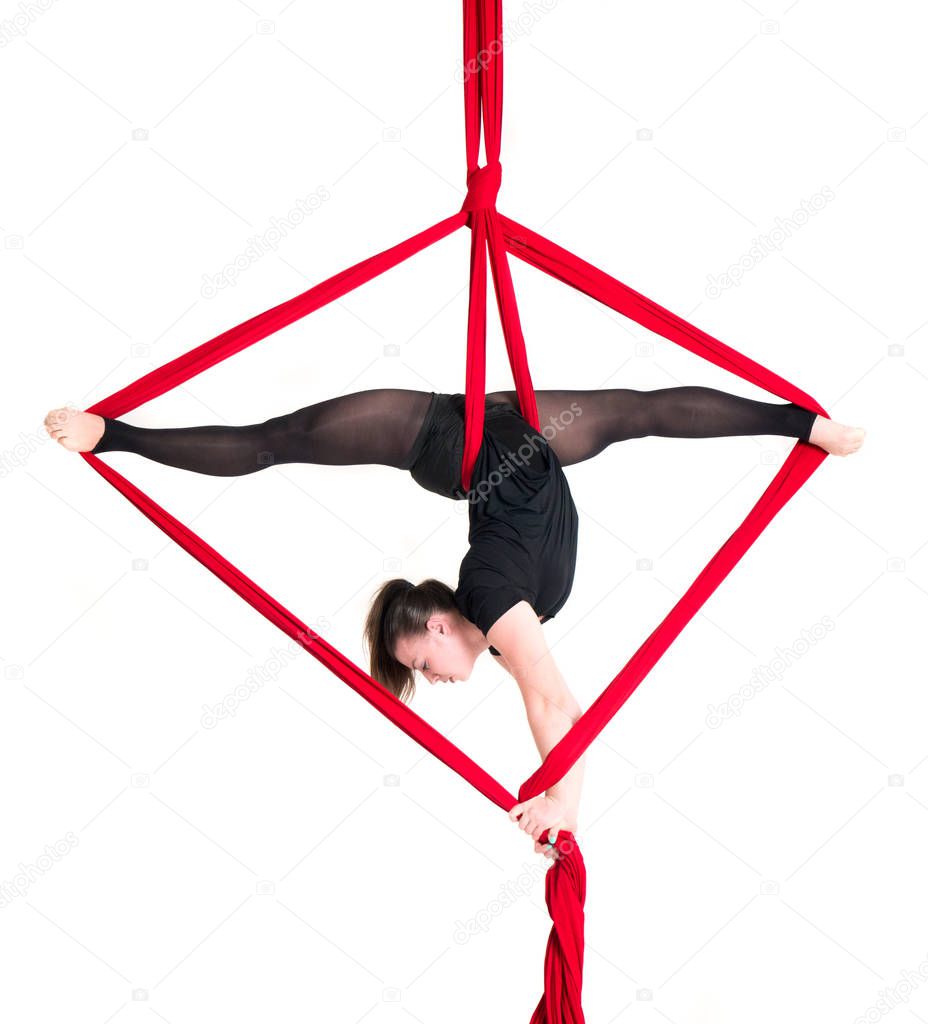 Woman hanging in aerial silks, isolated on white