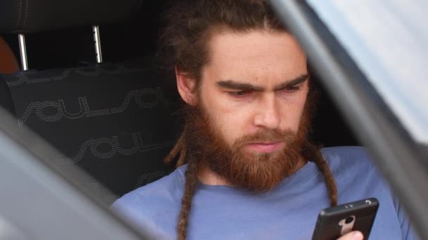 젊은 턱수염이 난된 남자는 차에 앉아서 전화에 메시지를 다이얼 — 비디오