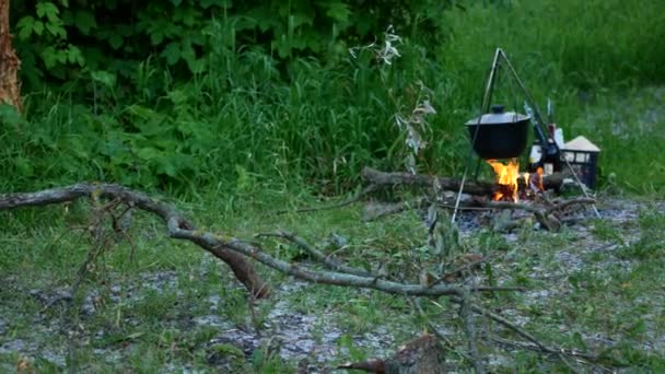たき火で観光鍋で屋外料理を調理します。野生性へのハイキング中に火災にキャンプ食品を準備するプロセス. — ストック動画