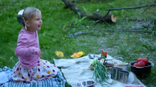 Маленька дівчинка в туристичному таборі лежить на столі — стокове відео