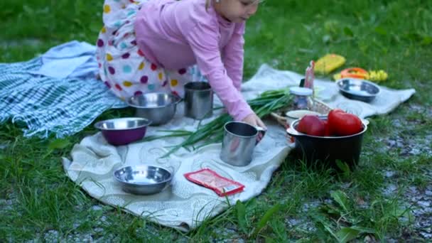 Una niña en el campamento turístico está tendida sobre la mesa. — Vídeos de Stock