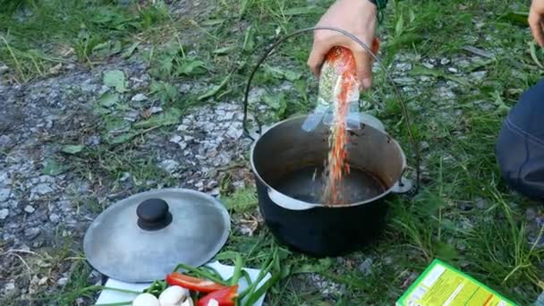 Kochen im Ferienlager. ein Mann gießt eine Packung Bohnen in einen Topf — Stockvideo