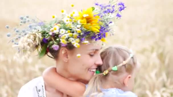 Mom and daughter are hugging in a wheat field. Mother in the national wreath — Stock Video