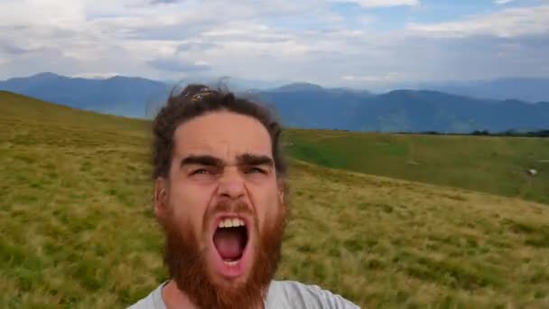 Um homem faz selfie nas montanhas. Vídeo alegre, vire um círculo — Vídeo de Stock