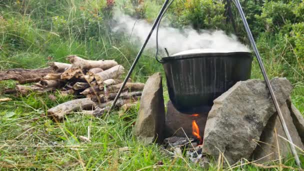 Cozinhar comida ao ar livre em panela turística na fogueira. Processo de preparação de alimentos de acampamento em fogo ardente enquanto caminhadas para a natureza selvagem — Vídeo de Stock